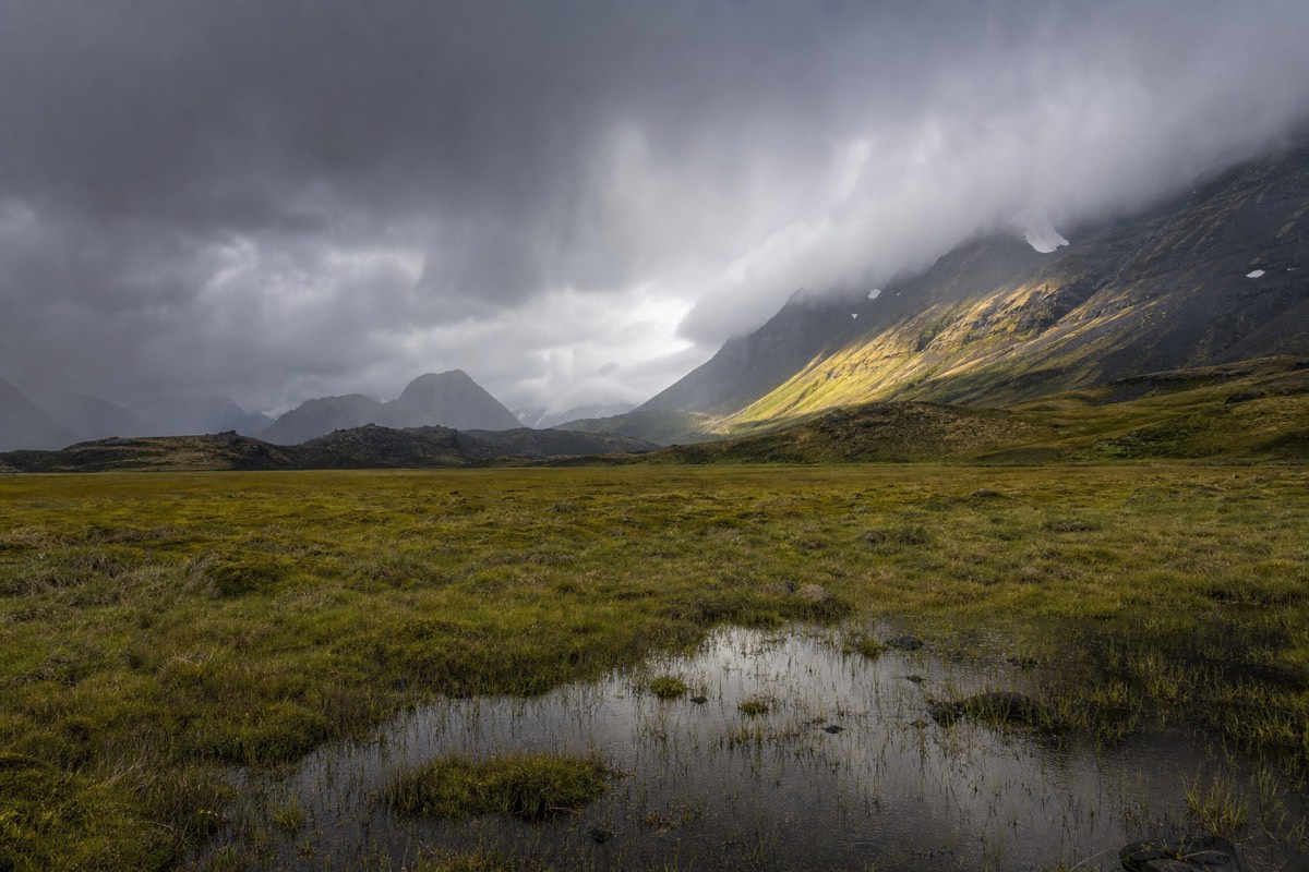 A rain squall sweeping across the granite massif under low grey cloud
