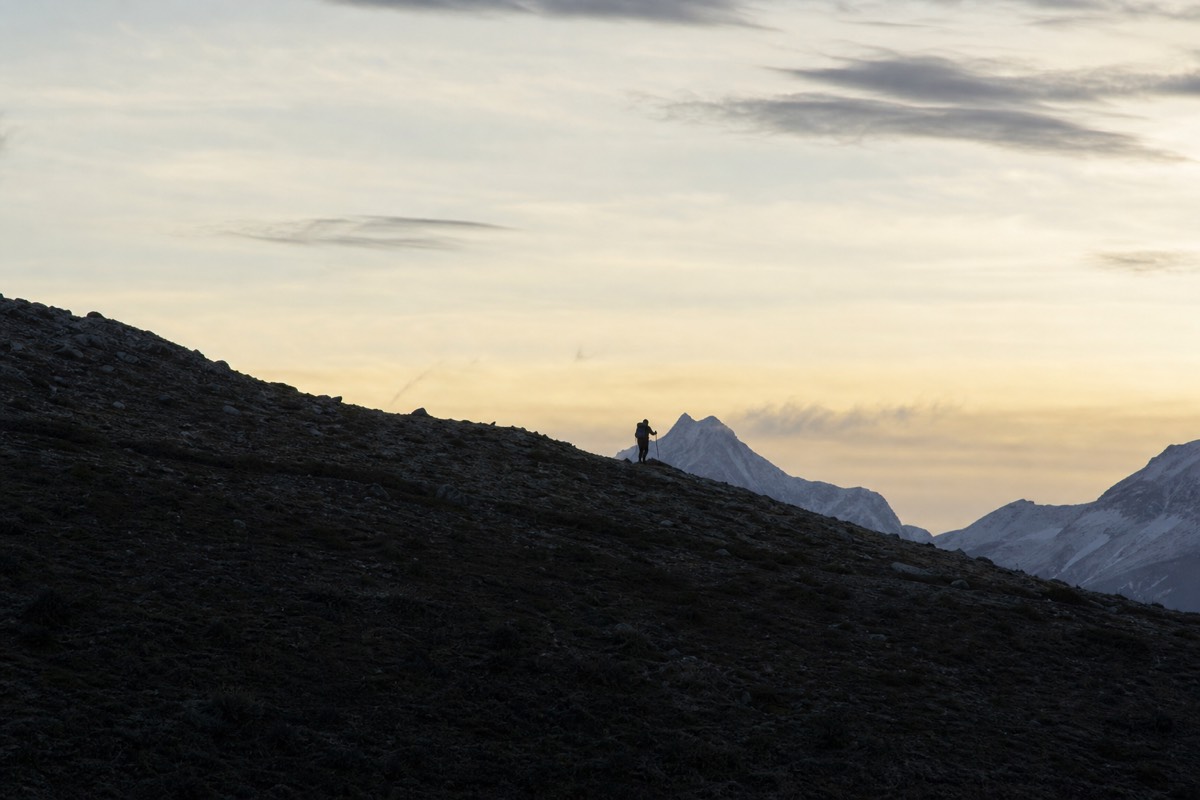 A lone hiker silhouetted on a ridge line above open Patagonian country at dusk